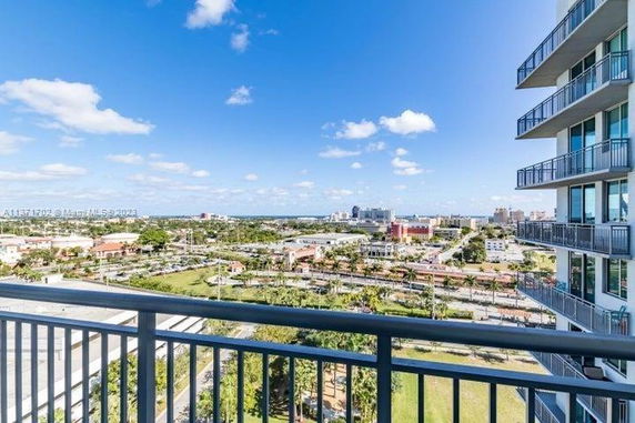 View from a balcony overlooking a cityscape with buildings and green areas.