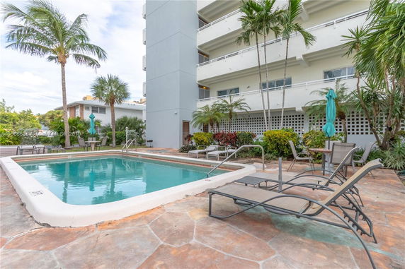 Outdoor swimming pool area with lounge chairs and surrounding greenery.