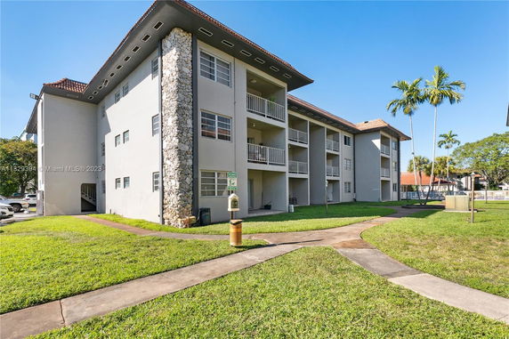 Front view of a multi-story building with balconies and a stone facade feature.