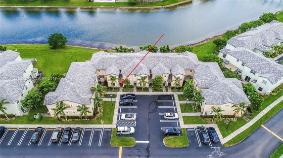 Aerial view of residential buildings with parking area and water body.