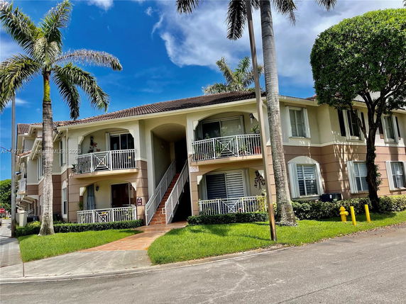 Front view of a two-story residential building with balconies and an exterior staircase.