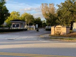 Entrance view of a gated community with a small guardhouse.