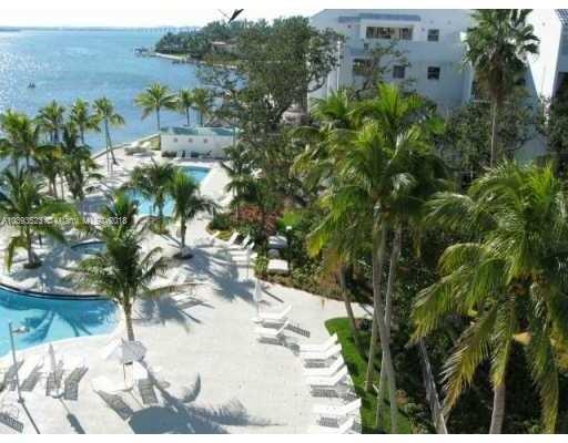 View of a coastal building area with a swimming pool and palm trees.