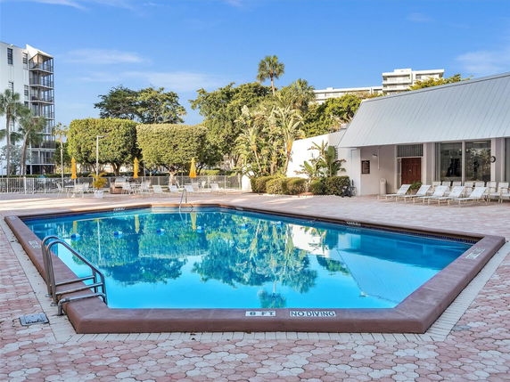 Outdoor swimming pool area with lounge chairs and surrounding greenery.