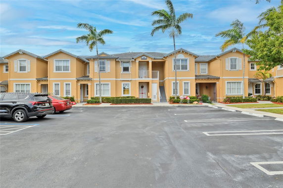 Front view of a two-story residential building with balconies and parking area.
