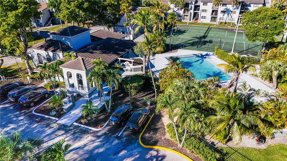 Aerial view of a complex with a swimming pool, tennis courts, and parking area.