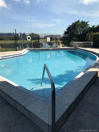 Outdoor swimming pool with surrounding fence and nearby water view.