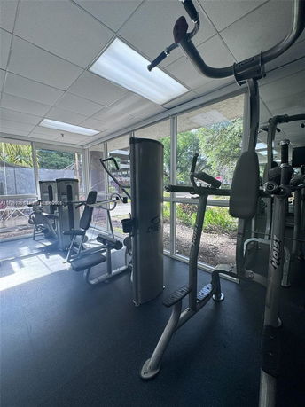 Indoor gym area with exercise machines and large windows.
