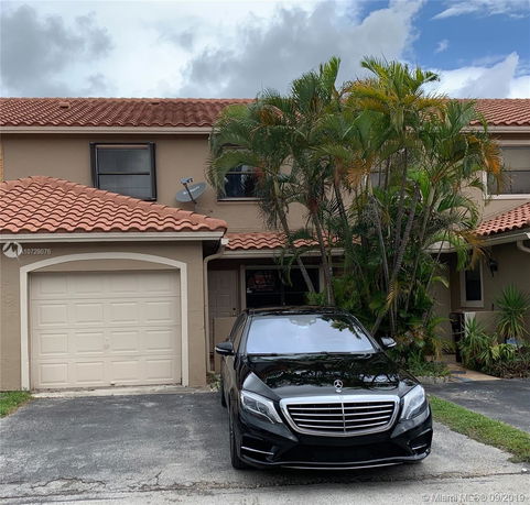 Front view of a two-story house with a garage and a car parked in the driveway.