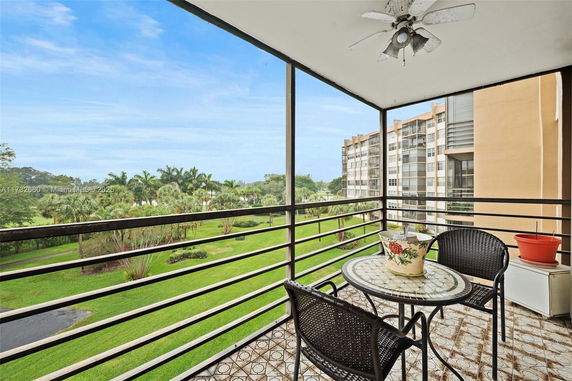 View from a balcony overlooking a green landscaped area and nearby buildings.