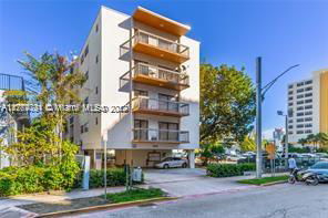 Front view of a multi-story apartment building with balconies and parking area underneath.
