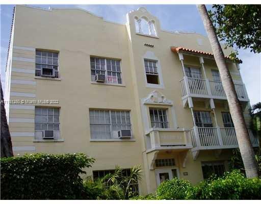 Front view of a three-story building with balconies and decorative architectural features.