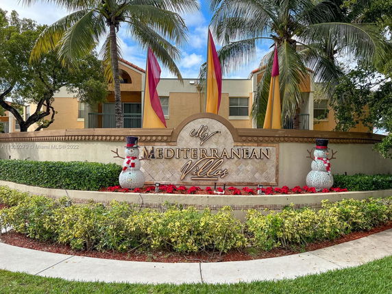 Front view of a building with a decorative sign for Mediterranean Villas, featuring holiday-themed decorations and palm trees.