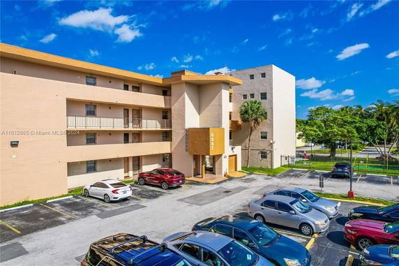 Front view of a multi-story apartment building with a parking lot in front.