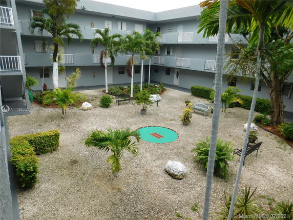 Courtyard view of a multi-story building with balconies and tropical landscaping.