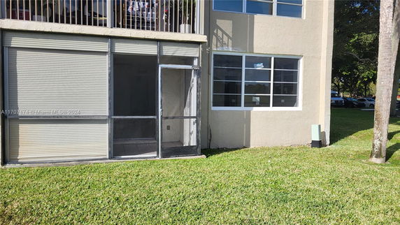 Exterior view of a building with ground-floor screen porch and upper-floor balcony.