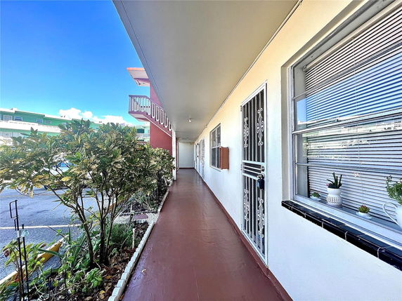 Exterior view of a multi-story building corridor with windows and plants.