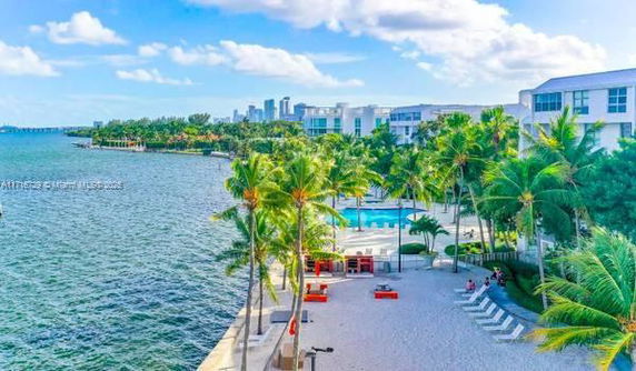 View of waterfront area with buildings, palm trees, and a pool.