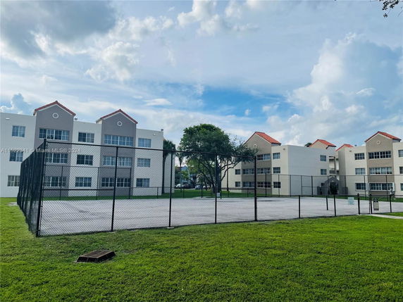 View of an outdoor tennis court with adjacent multi-story residential buildings.