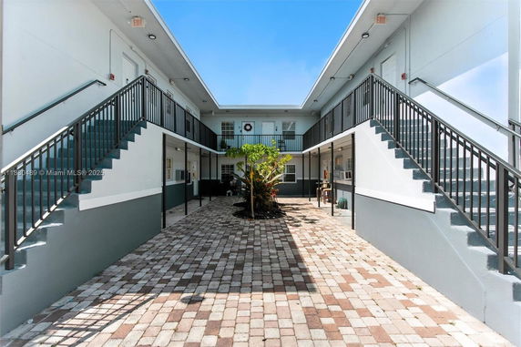 Front view of a two-story building with staircases leading to the upper level and a courtyard in the center.