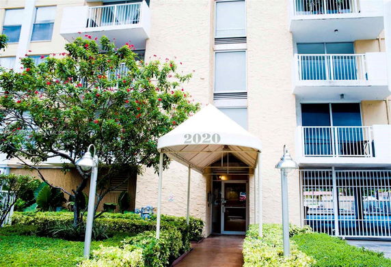 Front view of a multi-story building with balconies and a covered entrance marked '2020'.