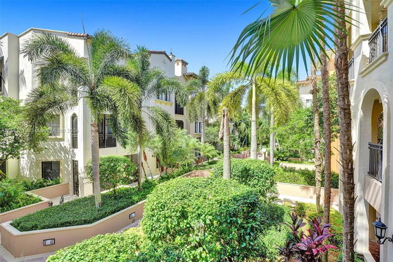 View of residential building surrounded by lush tropical vegetation and palm trees.