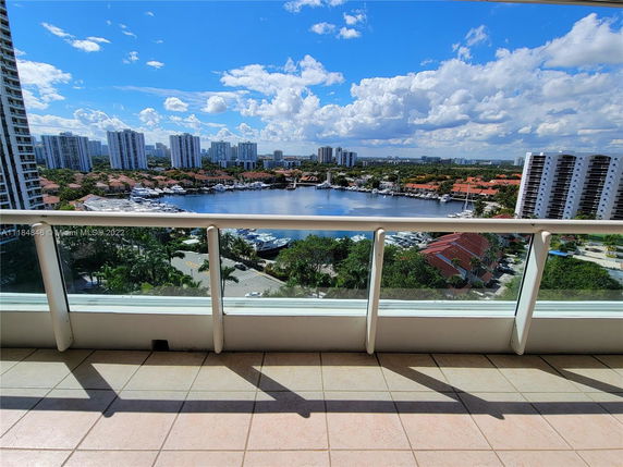 Balcony view over a waterfront area with surrounding buildings and a marina.