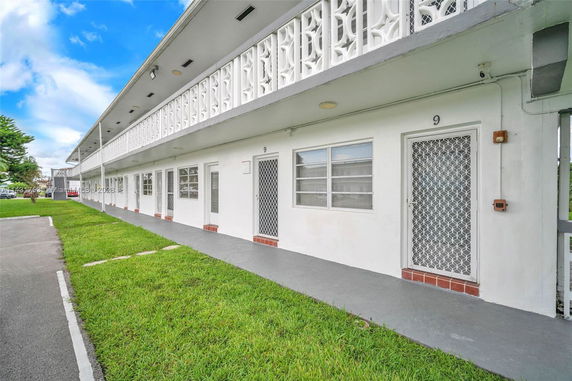 Front view of a two-story building with white facade and metal door grilles.