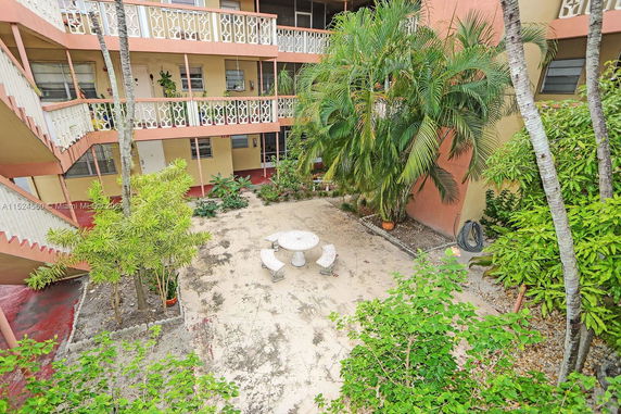 Inner courtyard view of a multi-story residential building with balconies and tropical plants.