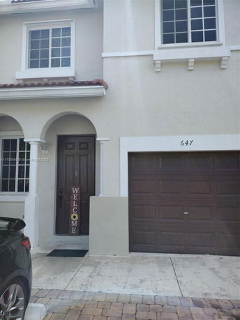 Front view of a two-story house with a garage and welcome sign.