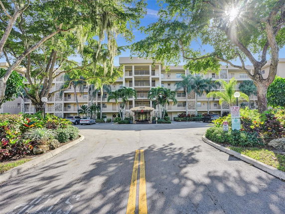 Front view of a multi-story residential building with balconies and landscaped entrance.