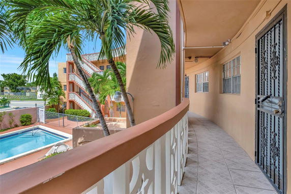 Outdoor view of an apartment building with a swimming pool and palm trees.