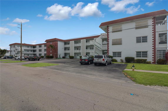 Front view of a three-story apartment building with external staircases and parking area.