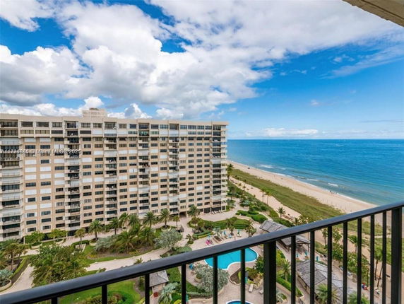 Panoramic view of a beachfront high-rise building with swimming pools and coastline.