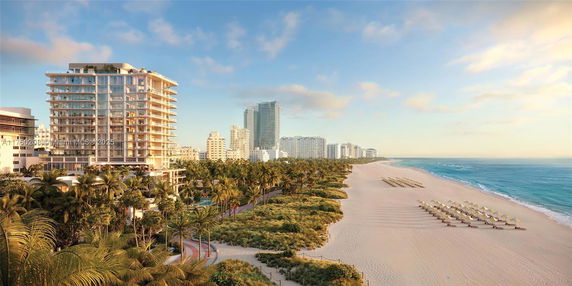 Scenic view of a beachfront area with modern buildings and a sandy beach lined with umbrellas.