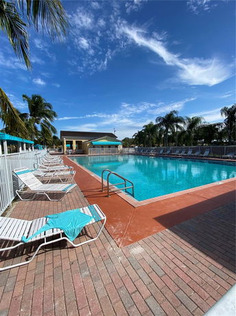 Outdoor swimming pool with lounge chairs and a building in the background.