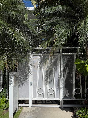 Front view of a building with a modern white gate and surrounding foliage.