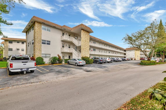 Front view of a multi-story apartment building with a parking area.