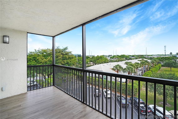 Rooftop view with a railing looking out over nearby buildings and a parking area.