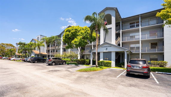 Front view of a multi-story residential building with balconies and parking area.