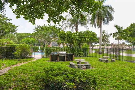 View of outdoor swimming pool area with surrounding greenery and seating.