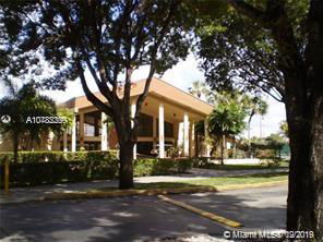 Front view of a two-story building with columns and surrounded by trees.