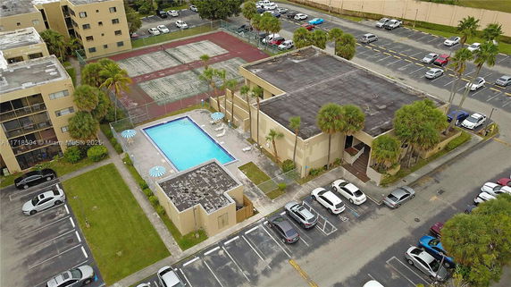Aerial view of a complex with a central swimming pool and surrounding buildings.