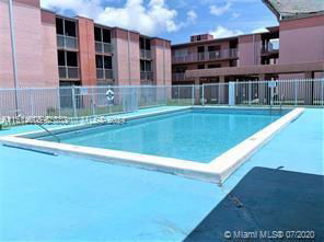 Outdoor swimming pool area in front of a multi-story residential building.