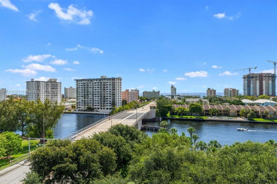 View of a river with a bridge and multiple high-rise buildings in the background.