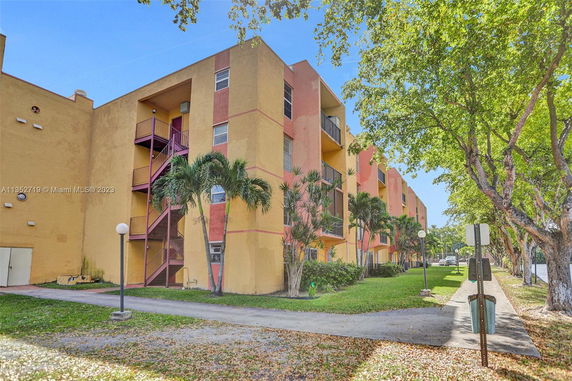 Front view of a multi-story apartment building with external stairs and balconies.