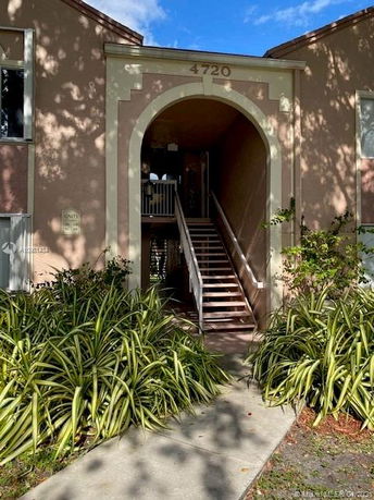 Front view of a building entrance with stairs and an archway.