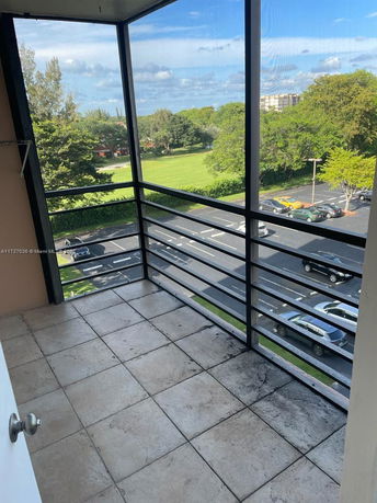 View from a balcony overlooking a park and parking area.
