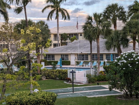 Outdoor view of a building with a swimming pool surrounded by palm trees.
