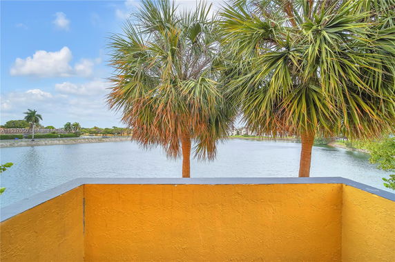 View from a balcony overlooking a body of water and palm trees.